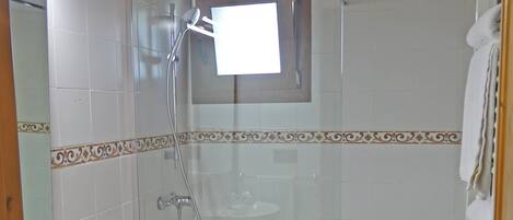 Une salle de bain comprenant des toilettes, un lavabo, une douche et une petite fenêtre.