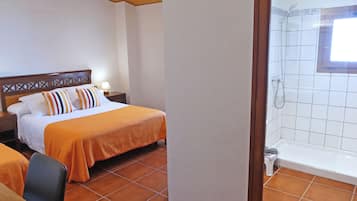 A hotel room with a bed, a nightstand, a chair, a bathroom with a bathtub, and a window.