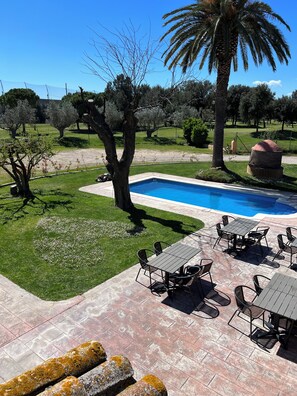 Un espace piscine doté d’un patio, de sièges extérieurs et d’un aménagement paysager verdoyant.