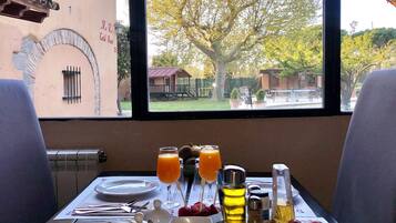 Una mesa de desayuno con vista a un árbol y edificios, incluyendo un letrero que dice "R.R. Cantina Restaurant".