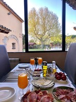 Una mesa de desayuno con vista a un árbol y edificios, incluyendo un letrero que dice "R.R. Cantina Restaurant".
