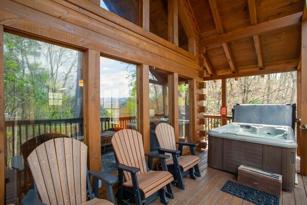 A covered outdoor seating area with Adirondack chairs and a hot tub.