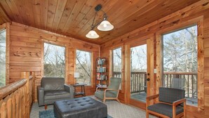 A cozy cabin interior with a leather sofa, a cushioned bench, and a wooden chair. - Blue Mist Lodge: Hot Tub, Outdoor Lounge, MORE (Sevierville)