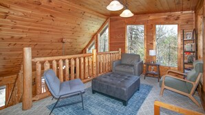 A cozy cabin interior with a wooden interior, a balcony with a wooden railing, and a seating area with a sofa and chairs. - Blue Mist Lodge: Hot Tub, Outdoor Lounge, MORE (Sevierville)