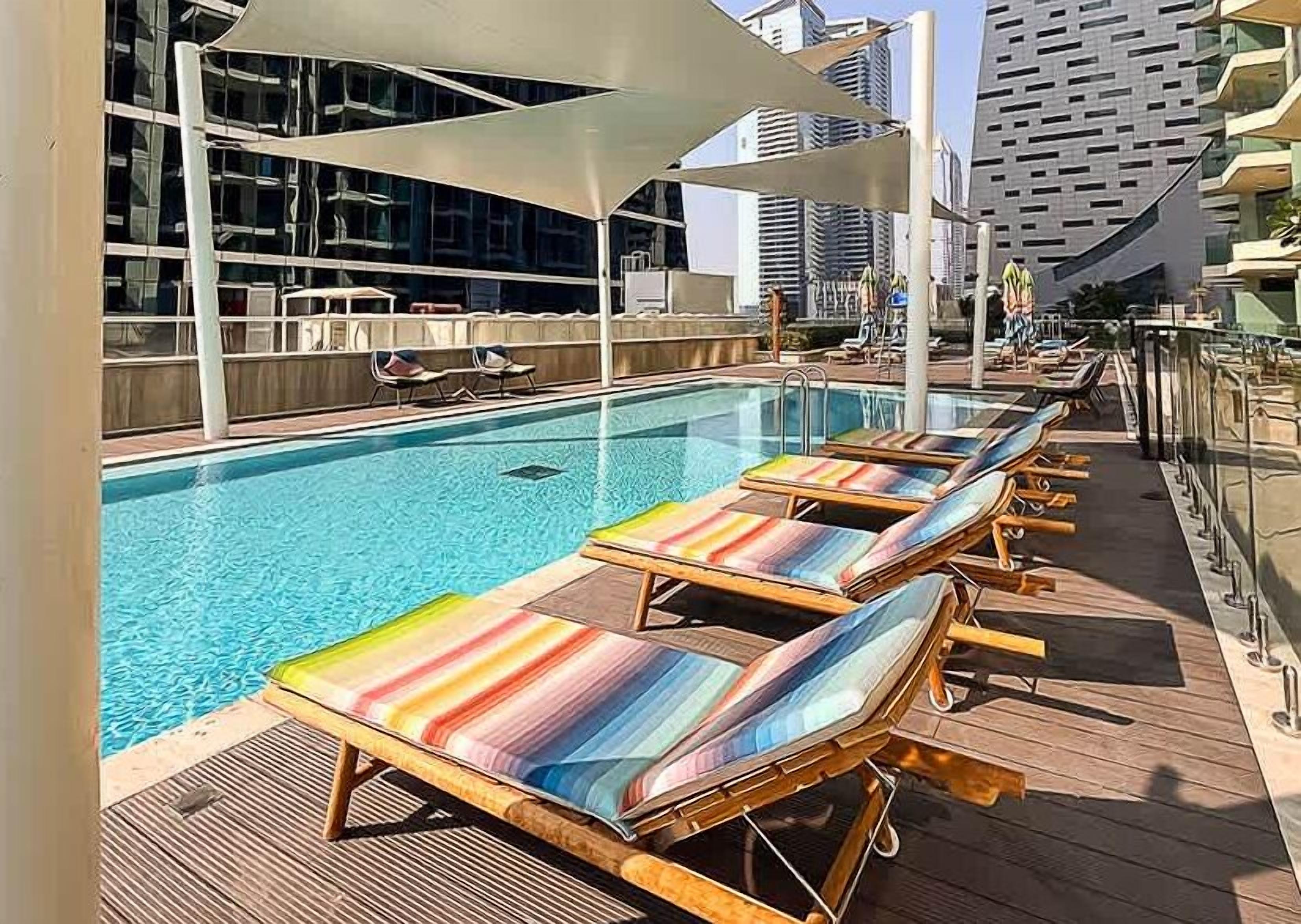 A rooftop pool area with lounge chairs and a view of the cityscape.