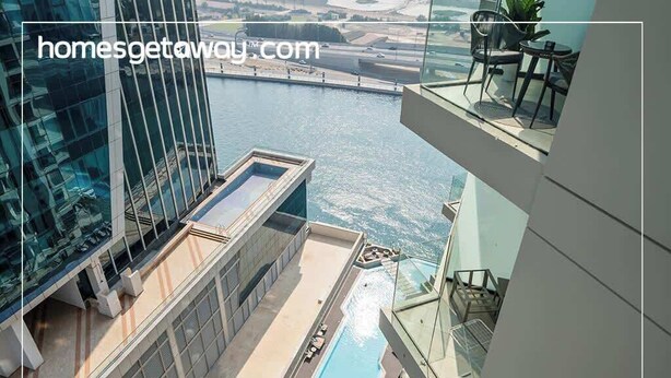 Een modern hotel met een dakterraszwembad, glazen hekwerk en uitzicht op een rivier.