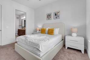 A bedroom with a bed, nightstands, a dresser, and artwork on the wall. - Beach Bliss: Modern 3 Bed Oasis Mins from Shore (Apollo Beach)