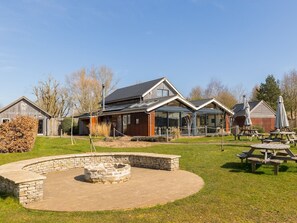 Un chalet doté d’un foyer en pierre, de tables de pique-nique et offrant une vue sur un ciel dégagé.