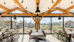 An outdoor dining area with wooden beams, large windows, and patterned floor tiles.