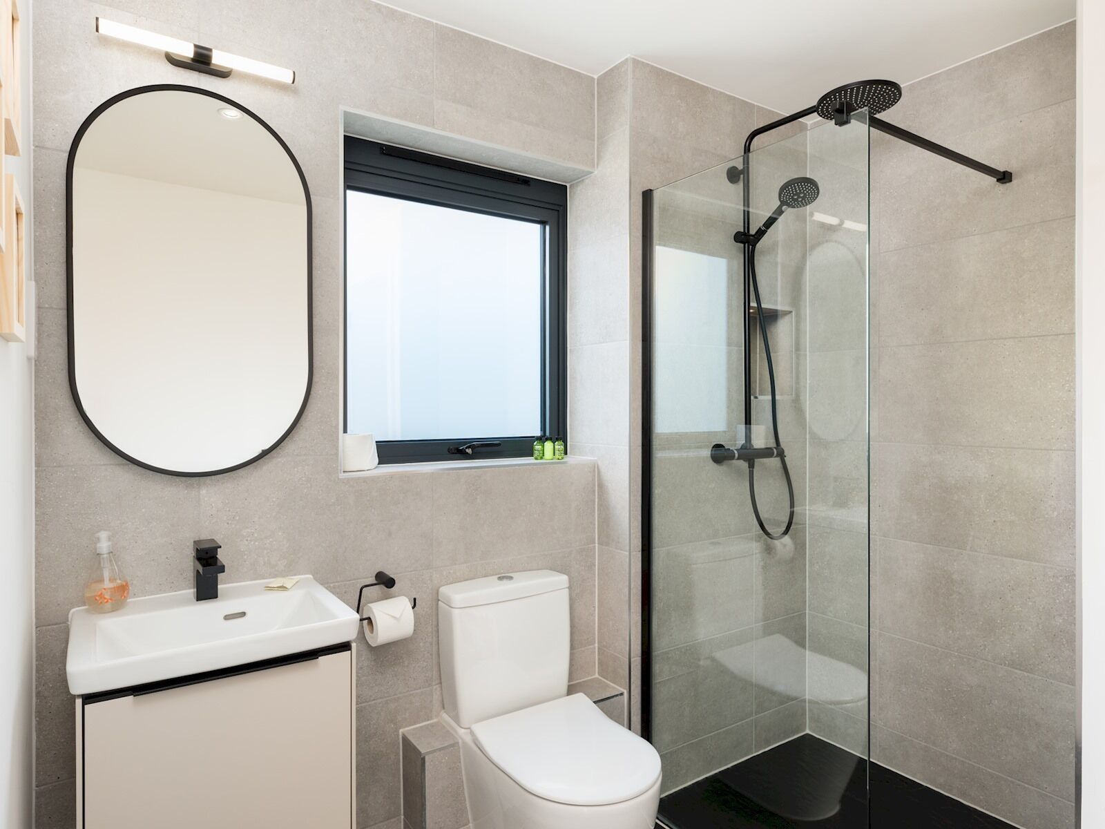 A modern bathroom with a toilet, sink, mirror, and glass-enclosed shower.