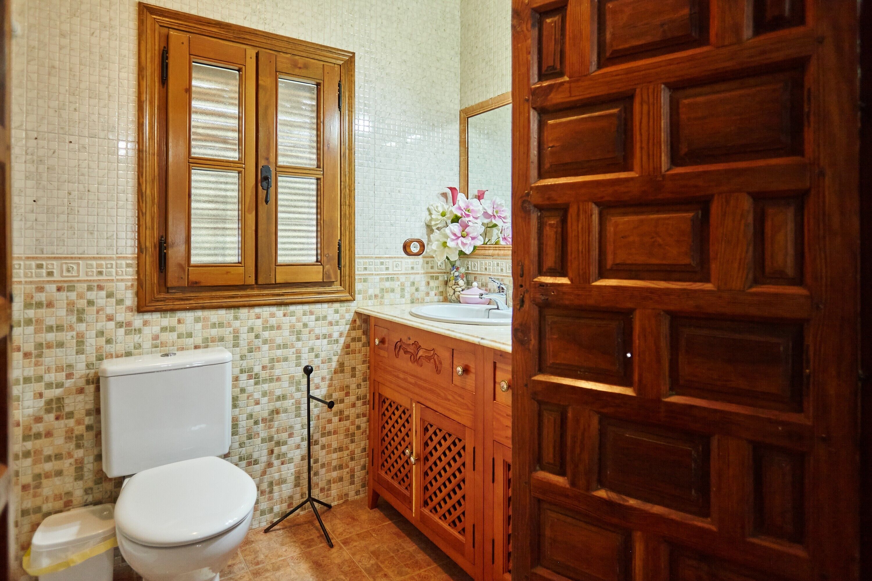 Een badkamer met toilet, wastafel, spiegel en een houten kastje.