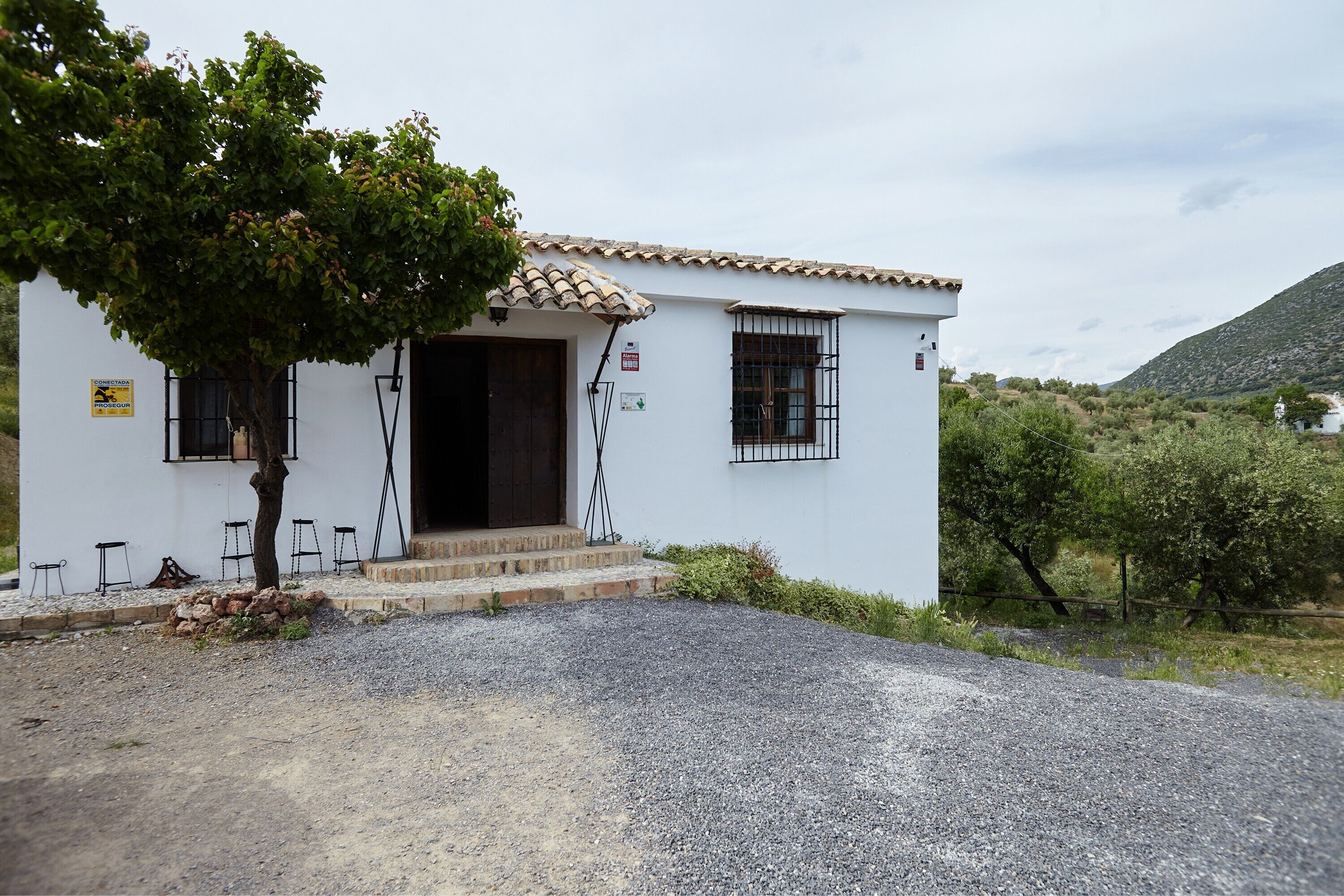 A white building with a tiled roof, a door, and windows with metal bars.