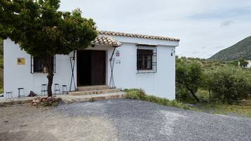 A white building with a tiled roof, a door, and windows with metal bars.