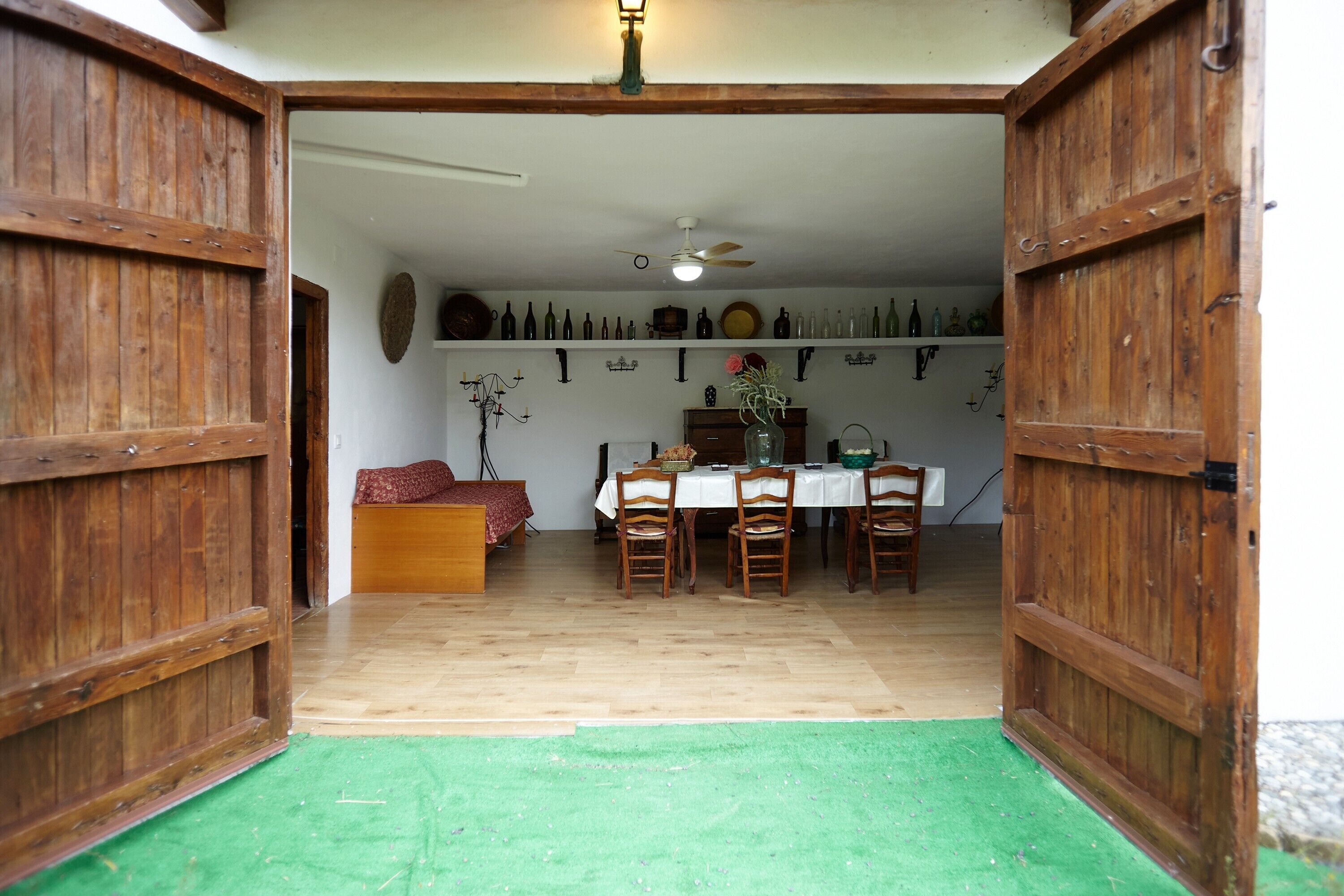 Une pièce avec une porte en bois, une table entourée de chaises, un canapé et un mur orné de divers objets.