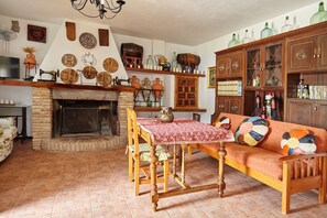 Uma sala de estar tradicional com lareira, mobiliário de madeira e objetos decorativos nas prateleiras.