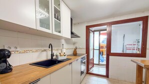 A modern kitchen with white cabinets, a wooden countertop, and a built-in oven.