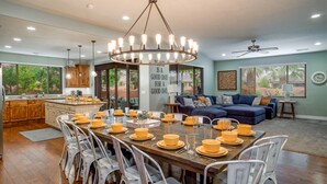A spacious dining area with a large wooden table set for a meal, surrounded by white chairs.