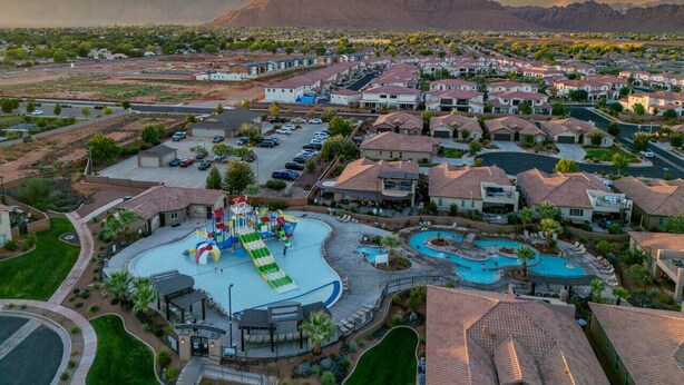 A residential area with a large swimming pool, a water park, and a mountain in the background.