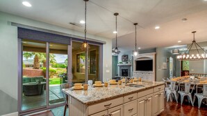 A spacious kitchen with a large island, sliding glass doors leading to a patio, and a dining area with a chandelier.