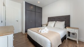 A hotel room with a large bed, a wardrobe, a bedside table, and a small desk.