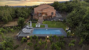 A villa with a swimming pool, outdoor seating, and a vineyard.