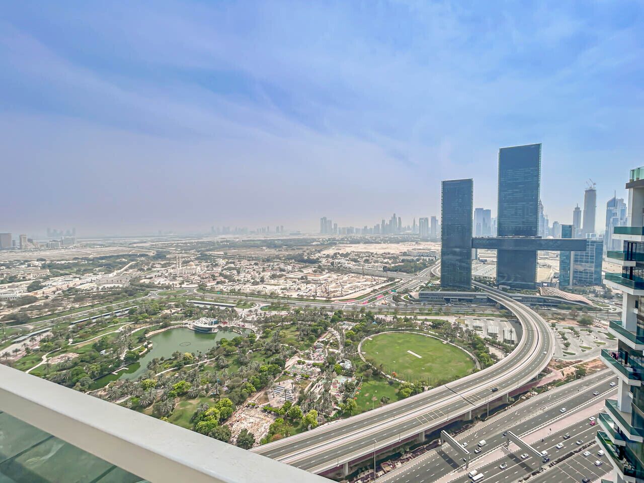 A cityscape with modern high-rise buildings, a curved highway, and a park area.