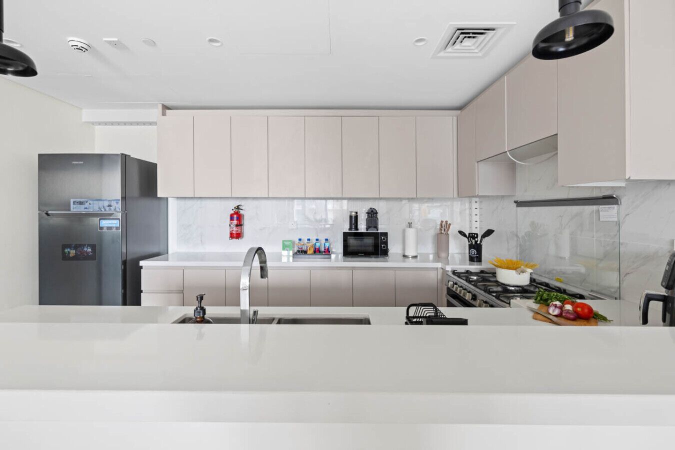 A modern kitchen with a stainless steel refrigerator, a sink, a microwave, and a stove.