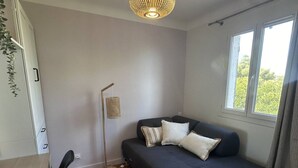 Une pièce moderne avec un canapé bleu foncé, une lampe sur pied et une fenêtre donnant sur un paysage verdoyant.