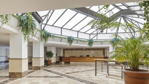 A spacious lobby with a checkered floor, a reception desk, and hanging plants. - Apartment in Terrazas de Banús for 4 people |4-12 (Puerto Banús - Marbella)