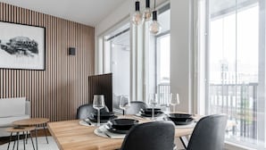 A modern dining area with a wooden table, black chairs, and hanging pendant lights.