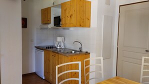 A compact kitchen with wooden cabinets, a built-in microwave, a coffee maker, and a sink.