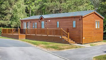 A wooden cabin with a porch, a staircase, and a fenced deck.