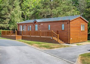Een houten hut met een veranda, een trap en een omheind terras.