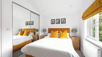 Une chambre à coucher avec un grand lit, deux tables de chevet, un miroir et une fenêtre avec des rideaux.