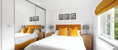 Un dormitorio con una cama grande, dos mesitas de noche, un espejo y una ventana con cortinas.