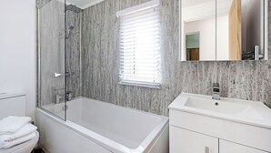 Une salle de bain moderne avec une douche à parois de verre, une baignoire blanche, un meuble-lavabo et un grand miroir.