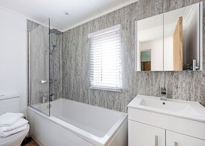 Een moderne badkamer met een douchecabine van glas, een witte badkuip, een wastafelmeubel met een wastafel en een grote spiegel.