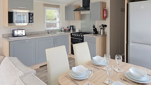 A modern kitchen with grey cabinets, a built-in oven, and a dining area with a table set for four.