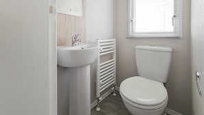 A bathroom with a white sink, toilet, and window with blinds.