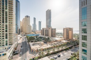 Zona urbana con edificios altos y modernos, una calle concurrida y un frente marítimo.