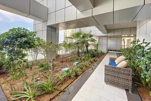 Un espacio exterior moderno con un sendero, asientos y diversas plantas.