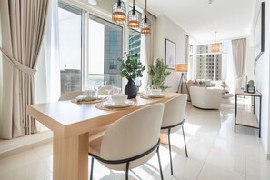 Un comedor moderno con una mesa de madera, sillas blancas y un florero con plantas.