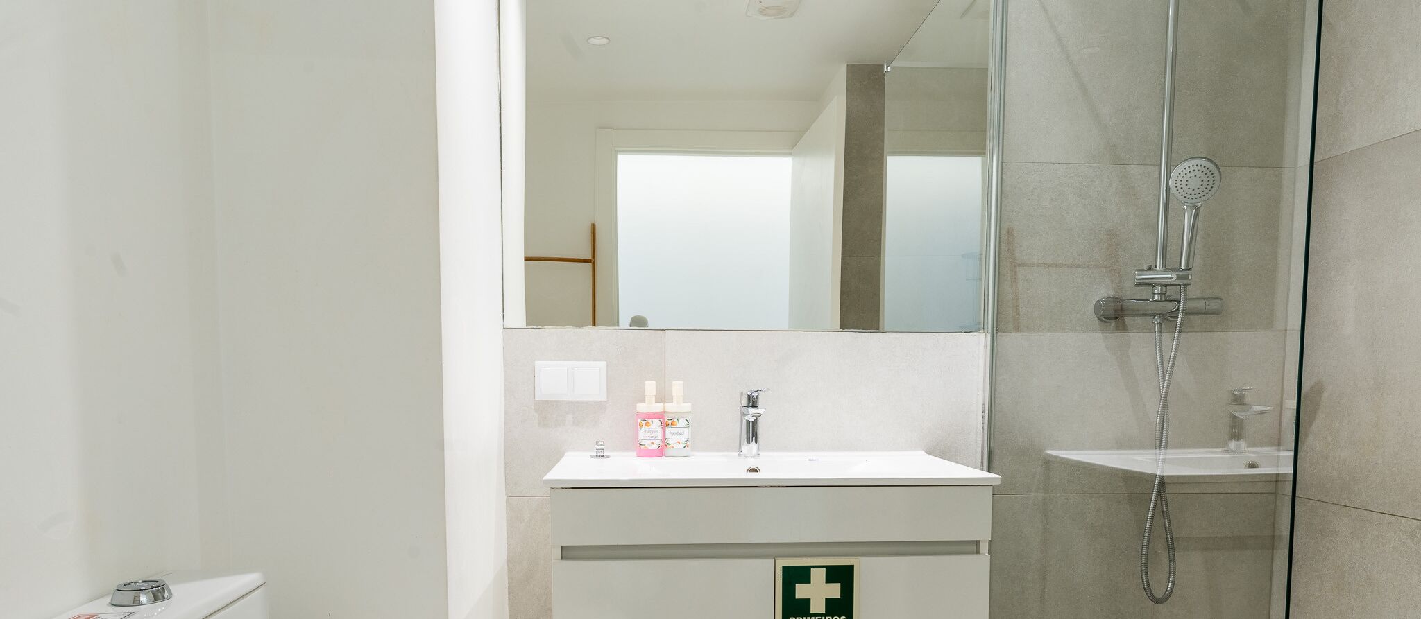 A modern bathroom with a glass-enclosed shower, a white sink, and a mirror above it.