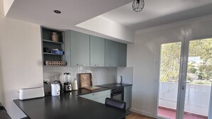 Eine moderne Küche mit grauen Schränken, einer schwarzen Arbeitsplatte und einem Essbereich mit schwarzem Tisch und Stühlen.