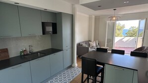 Eine moderne Küche mit grauen Schränken, einer schwarzen Arbeitsplatte und einem Essbereich mit Tisch und Stühlen.