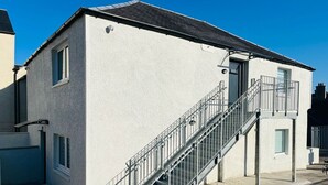 Ein Gebäude mit weißer Fassade, einer Metalltreppe und einem kleinen Balkon.