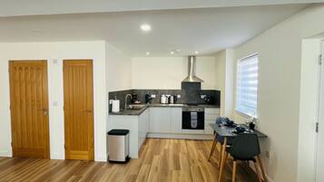 A compact kitchen with wooden flooring, a built-in oven, and a dining area with a table and chairs.