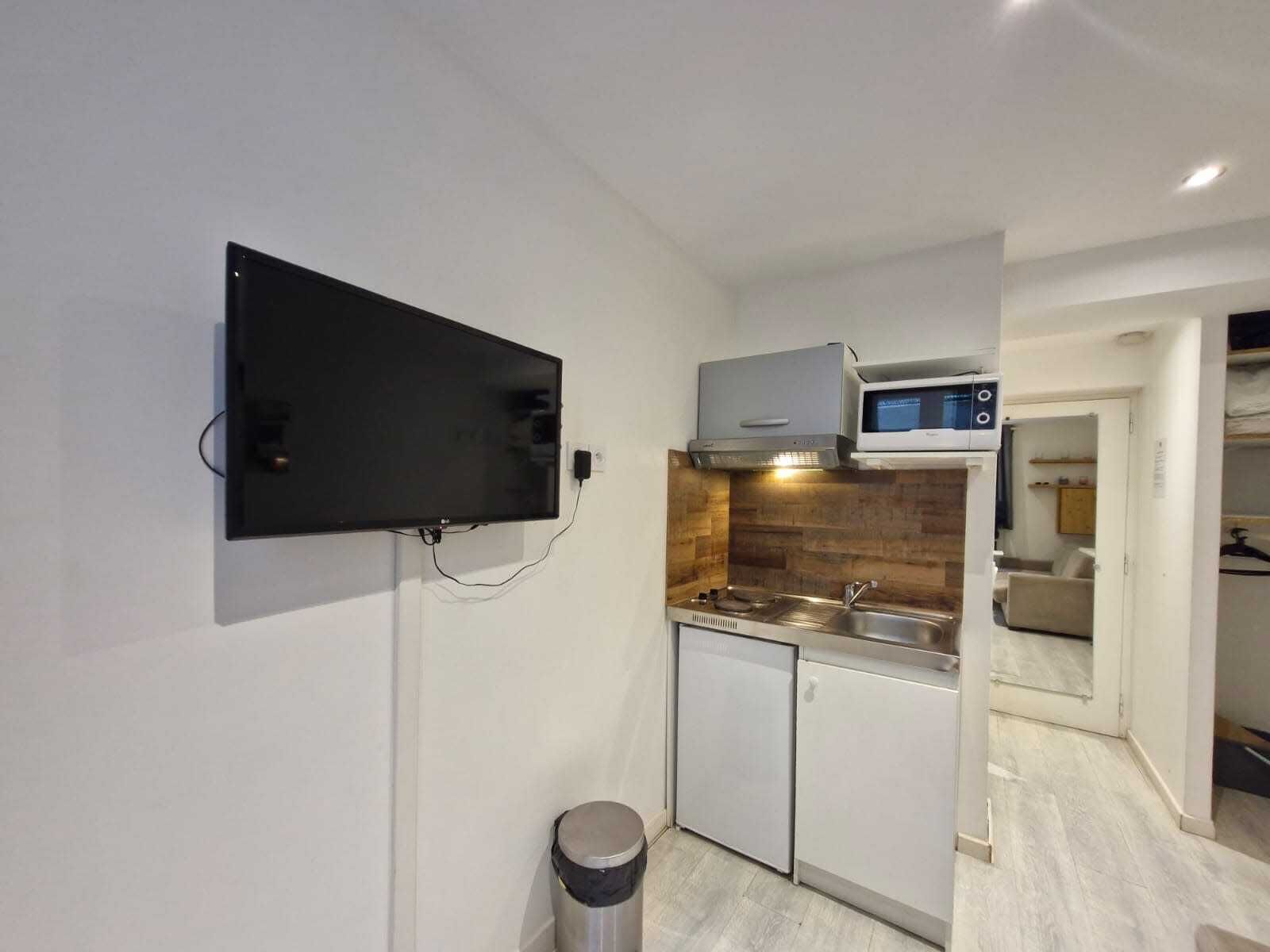 A modern kitchen with a built-in TV, stainless steel appliances, and a compact layout.