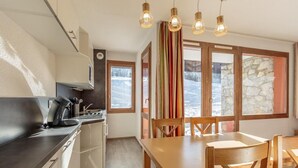 Cocina moderna con estufa, pileta y mesa de comedor de madera con sillas.
