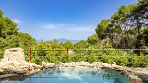A swimming pool with stone walls and a clear view of mountains in the background.